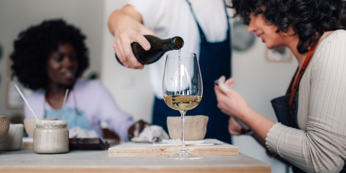 Close up of hand pouring wine into a wineglass on pottery class.