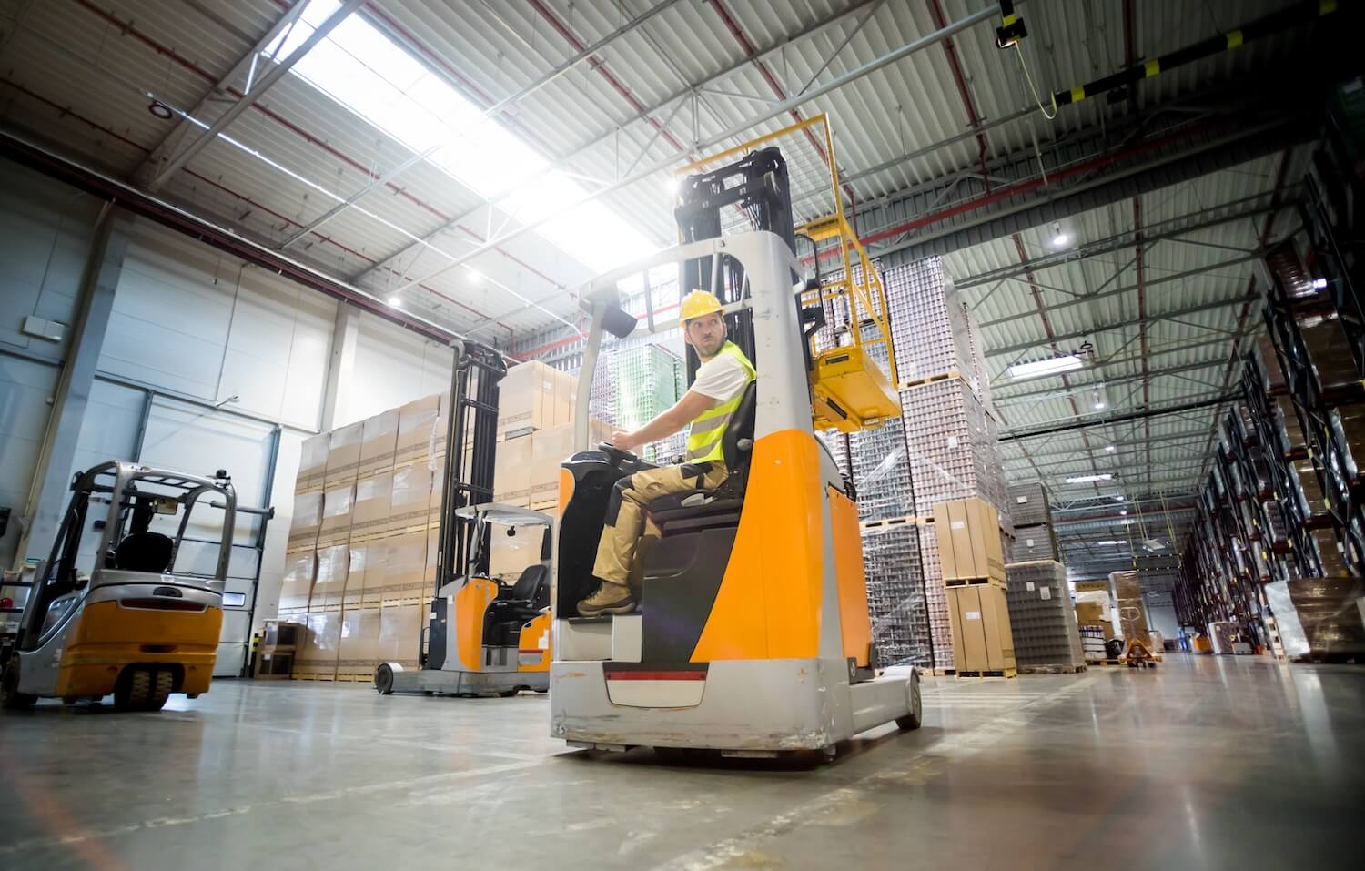 Man driving forklift in large brewery warehouse