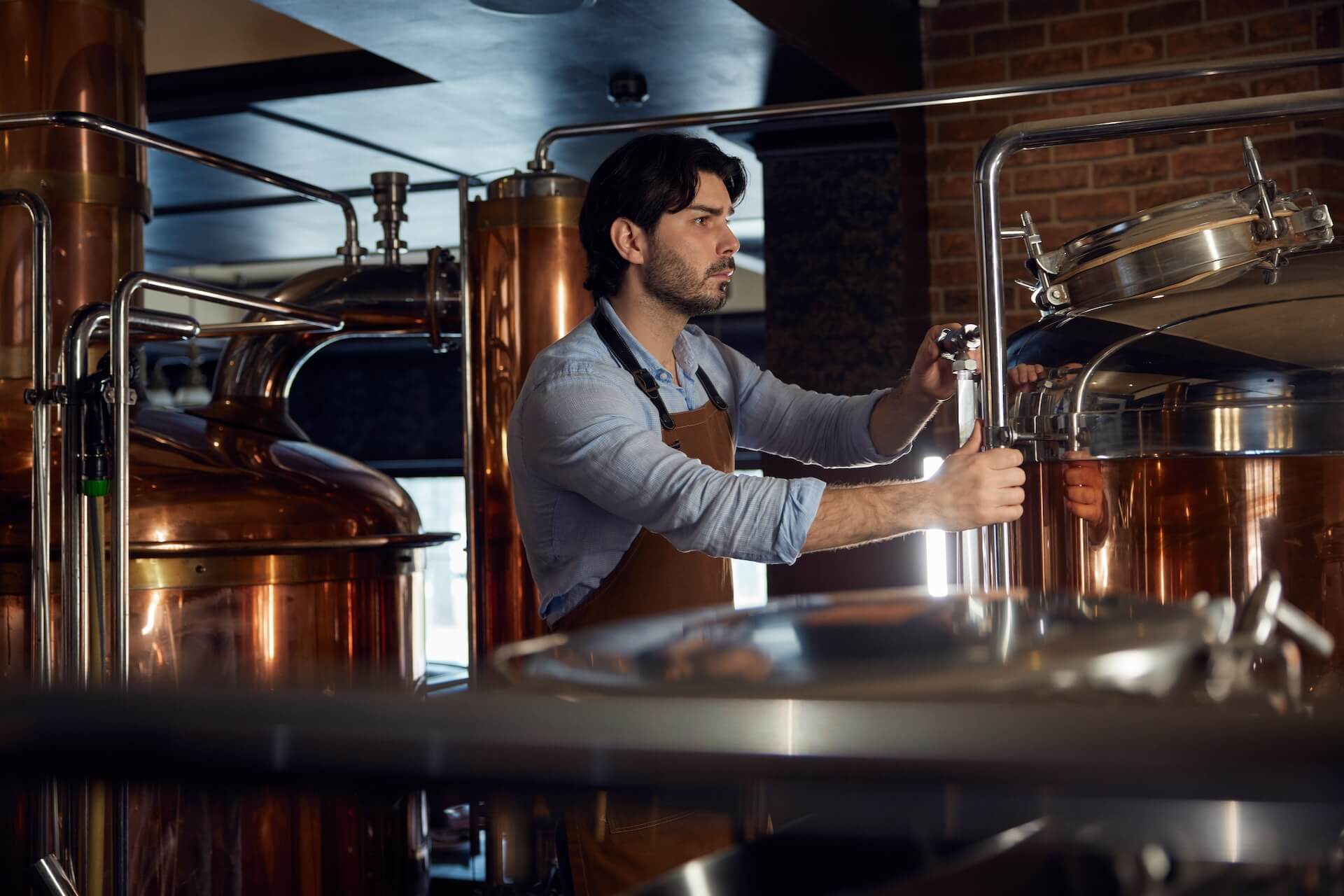 A man working in a craft distillery on a copper still. What the production floor taught us about building better distillery software